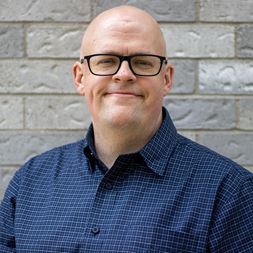 headshot photo of Colin with a brick wall in the background